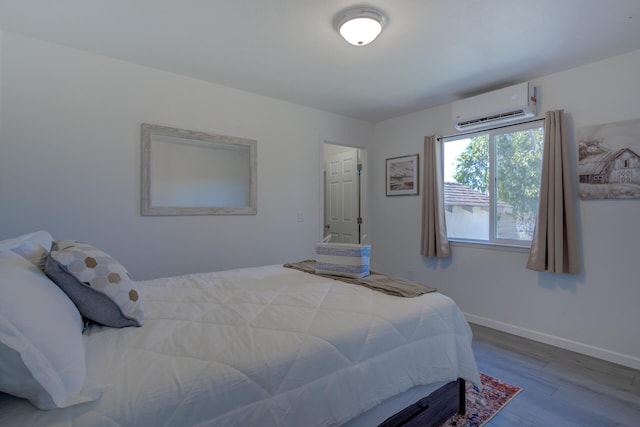 bedroom with an AC wall unit, wood finished floors, and baseboards