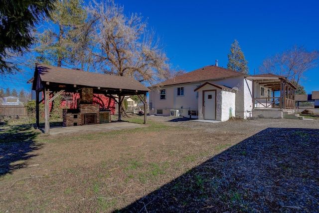 rear view of property with a patio, a lawn, a fireplace, and fence