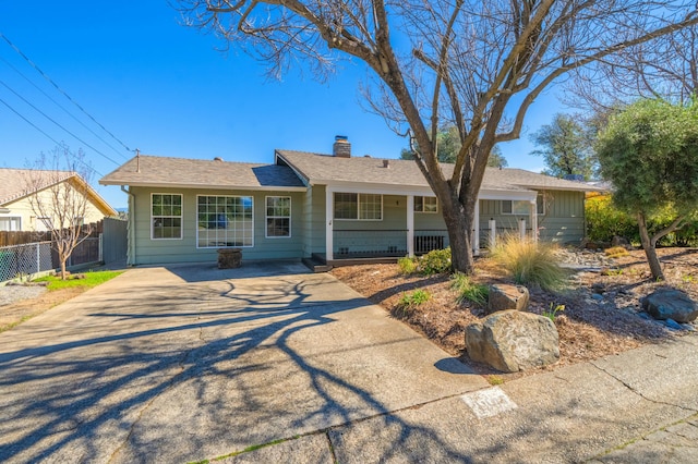 ranch-style house featuring driveway, a porch, a chimney, and fence