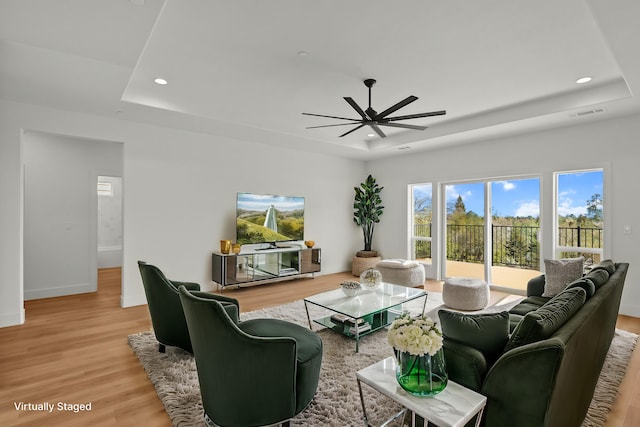 living area featuring visible vents, a tray ceiling, wood finished floors, and recessed lighting