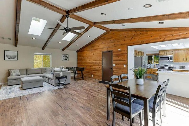 18260 Racoon Dr, Lakehead, CA 96051 - dining space featuring vaulted ceiling with skylight, visible vents, light wood-style flooring, ceiling fan, and wood walls