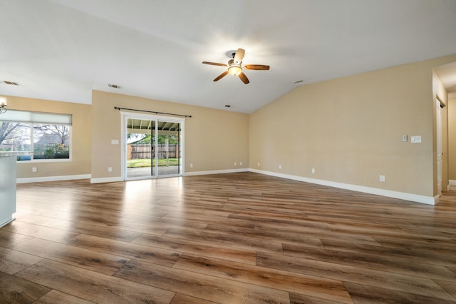 unfurnished room with ceiling fan with notable chandelier, wood finished floors, visible vents, baseboards, and vaulted ceiling