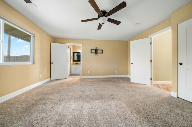 interior space with light colored carpet, visible vents, a ceiling fan, connected bathroom, and baseboards