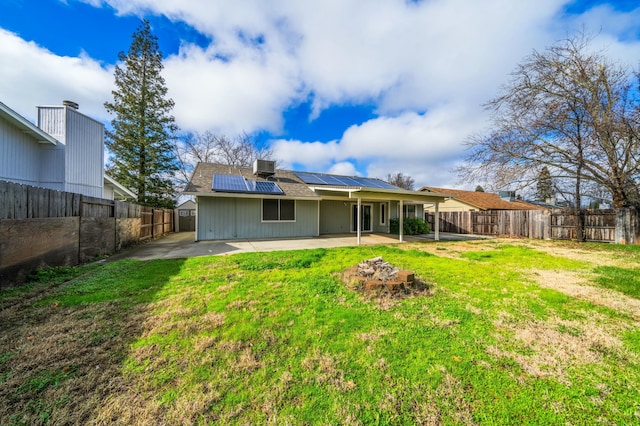 back of property featuring a patio area, a lawn, a fenced backyard, and solar panels