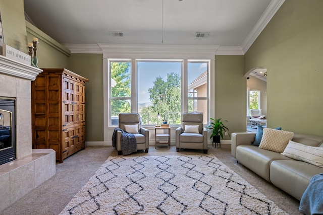 living area with carpet floors, arched walkways, visible vents, ornamental molding, and a high end fireplace