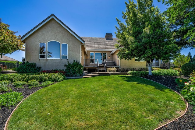 view of front of property featuring a deck, a chimney, a front yard, and stucco siding