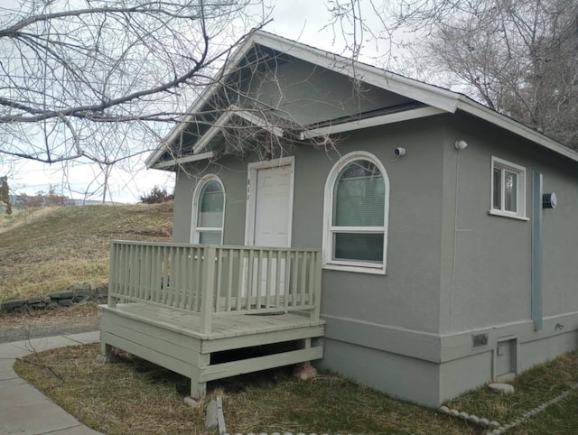 view of home's exterior with crawl space, stucco siding, and a wooden deck