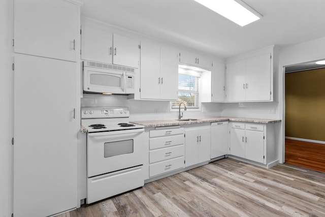 kitchen with white appliances, light countertops, light wood-style flooring, and white cabinetry