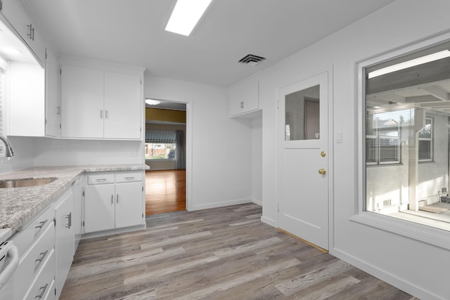 kitchen with visible vents, a sink, light wood-style flooring, and white cabinetry