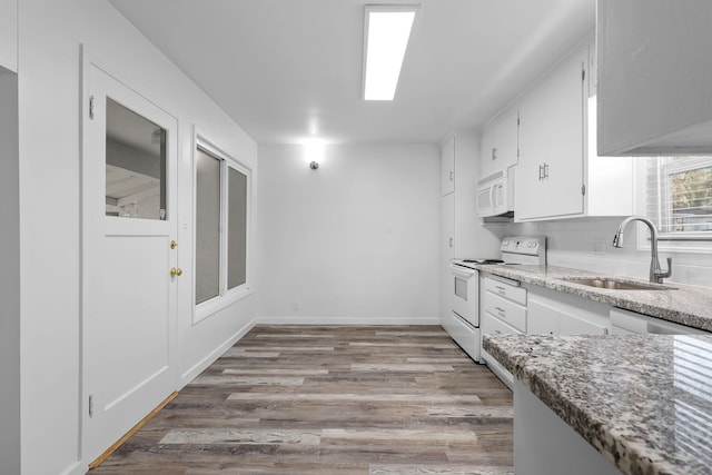 kitchen with white appliances, white cabinets, light stone counters, light wood-type flooring, and a sink