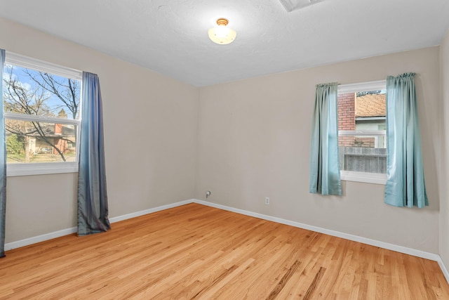 empty room with light wood-type flooring, visible vents, and baseboards