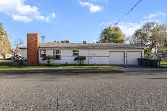 ranch-style house featuring a garage, driveway, crawl space, and a chimney