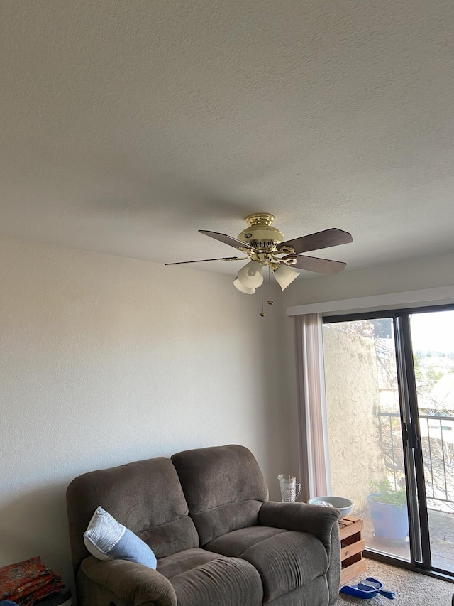 living area with a ceiling fan, a textured ceiling, and carpet flooring