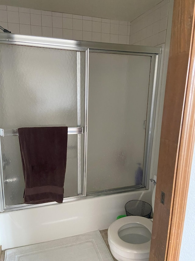 full bath with toilet and bath / shower combo with glass door