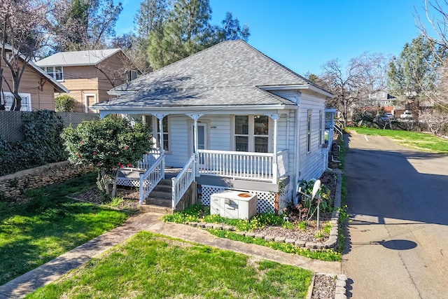 bungalow-style house featuring a porch, roof with shingles, and a front lawn