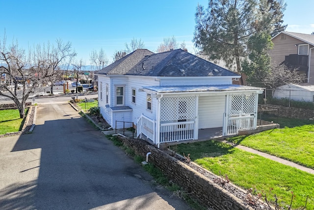 view of property exterior with a shingled roof and a lawn