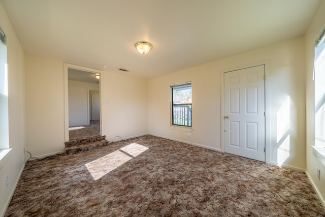 carpeted spare room featuring baseboards and visible vents