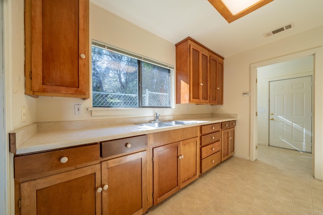 kitchen featuring light countertops, a sink, visible vents, and brown cabinets