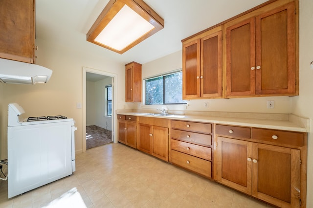 kitchen with light countertops, brown cabinetry, a sink, range, and under cabinet range hood