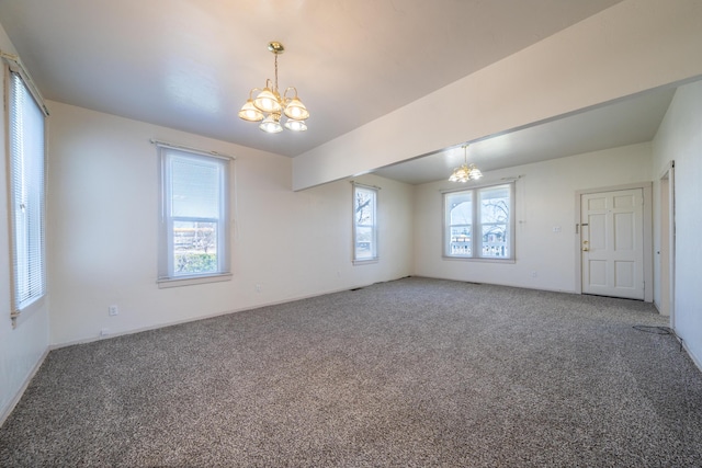 carpeted empty room featuring a chandelier