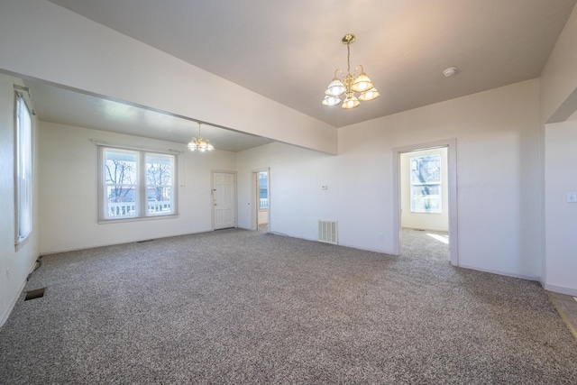 empty room with carpet, visible vents, and a notable chandelier