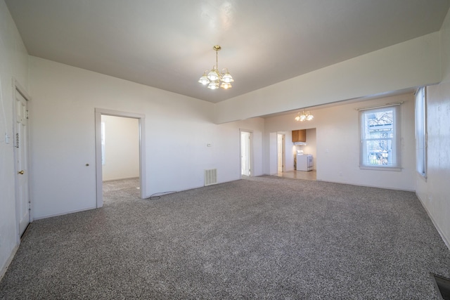 carpeted empty room with washer / dryer, visible vents, and a notable chandelier