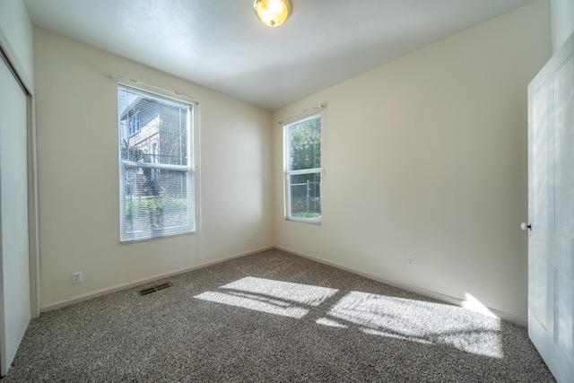 carpeted spare room featuring baseboards and visible vents