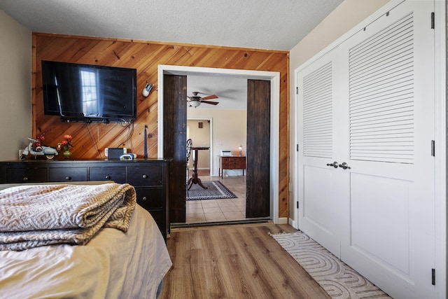 bedroom with a closet, wood walls, a textured ceiling, and wood finished floors