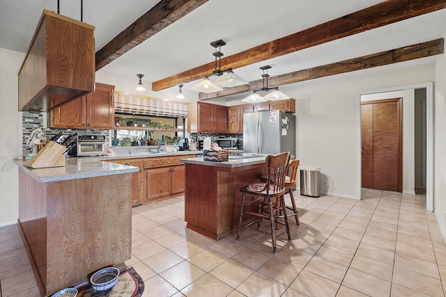 kitchen featuring a breakfast bar, light tile patterned floors, stainless steel appliances, backsplash, and brown cabinetry