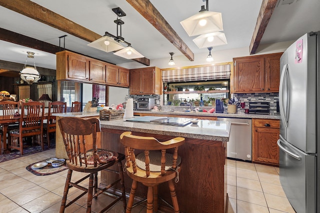 kitchen with light tile patterned floors, tasteful backsplash, appliances with stainless steel finishes, brown cabinetry, and beamed ceiling