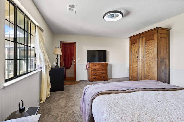 carpeted bedroom with a wainscoted wall and visible vents