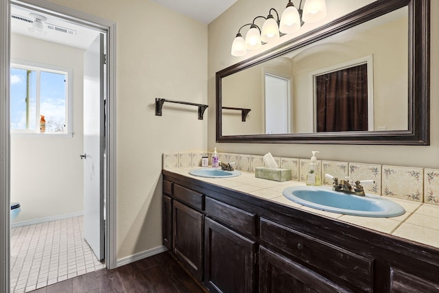 full bathroom with double vanity, baseboards, a sink, and wood finished floors