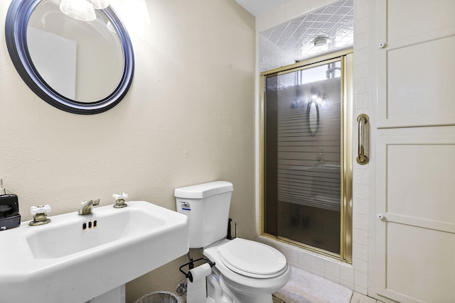 bathroom featuring toilet, a stall shower, a sink, and a textured wall