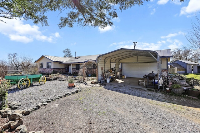 view of front facade with gravel driveway, metal roof, a carport, and an outbuilding