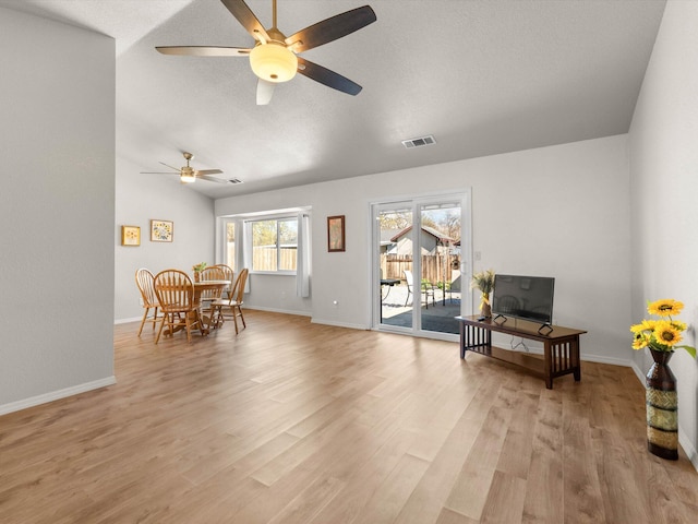 living area featuring light wood-style flooring, baseboards, visible vents, and a textured ceiling