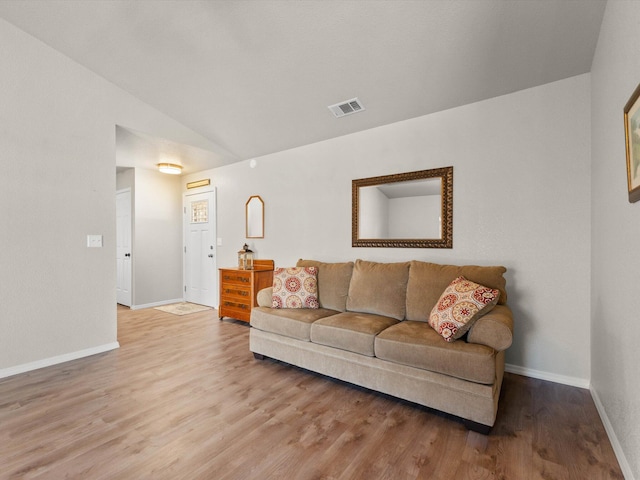 living area featuring visible vents, baseboards, lofted ceiling, and wood finished floors