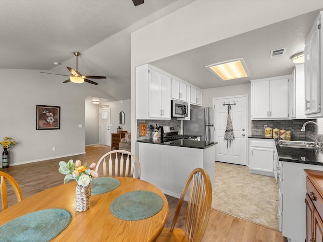 dining area with visible vents, light wood-style flooring, baseboards, lofted ceiling, and ceiling fan