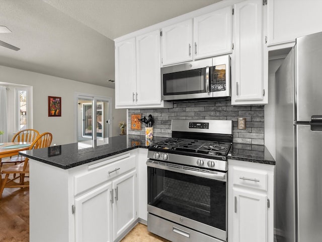 kitchen with a peninsula, white cabinets, tasteful backsplash, and stainless steel appliances