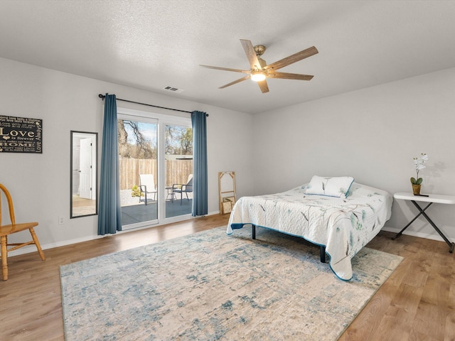 bedroom with access to exterior, visible vents, baseboards, light wood-style flooring, and a textured ceiling