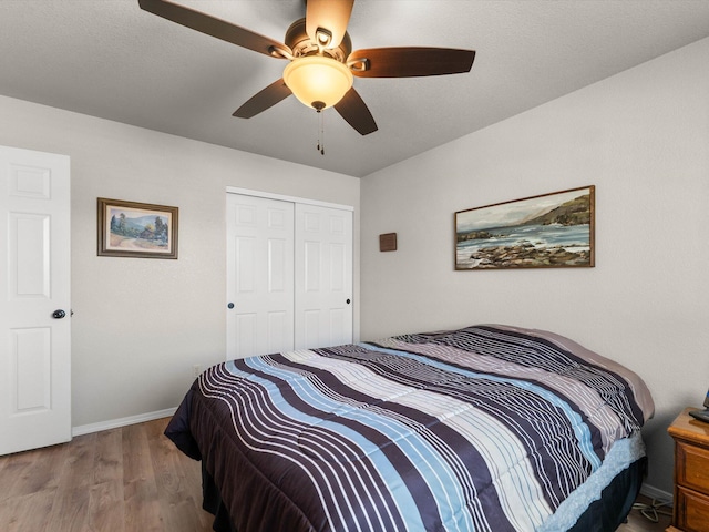 bedroom featuring a ceiling fan, wood finished floors, a closet, and baseboards