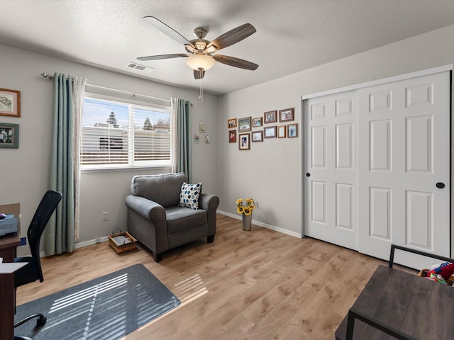 office space with light wood finished floors, visible vents, a textured ceiling, and baseboards