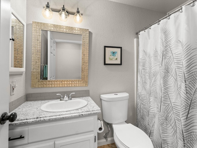 bathroom featuring toilet, vanity, and a textured wall