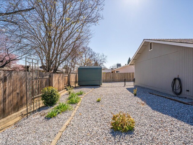 view of yard featuring an outbuilding, a storage unit, and a fenced backyard