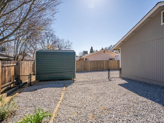 view of yard featuring a storage unit, an outbuilding, and a fenced backyard