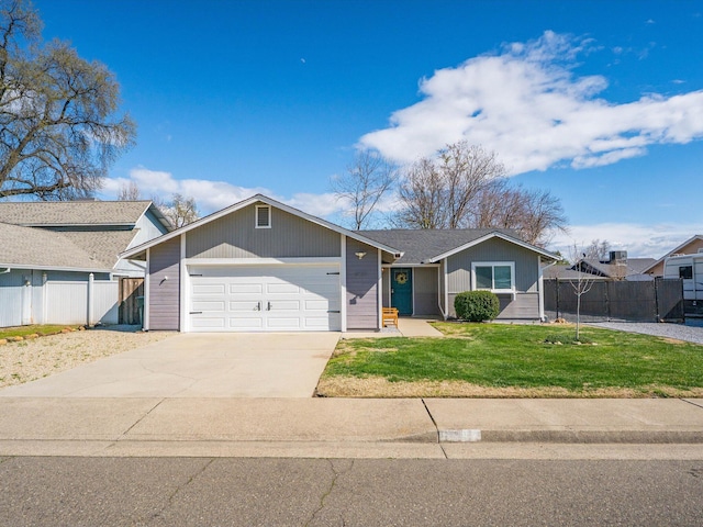 view of front of property with an attached garage, concrete driveway, a front lawn, and fence