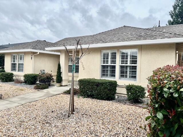 exterior space with roof with shingles and stucco siding