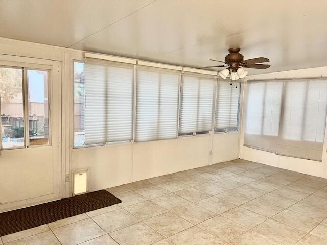 unfurnished sunroom featuring a ceiling fan