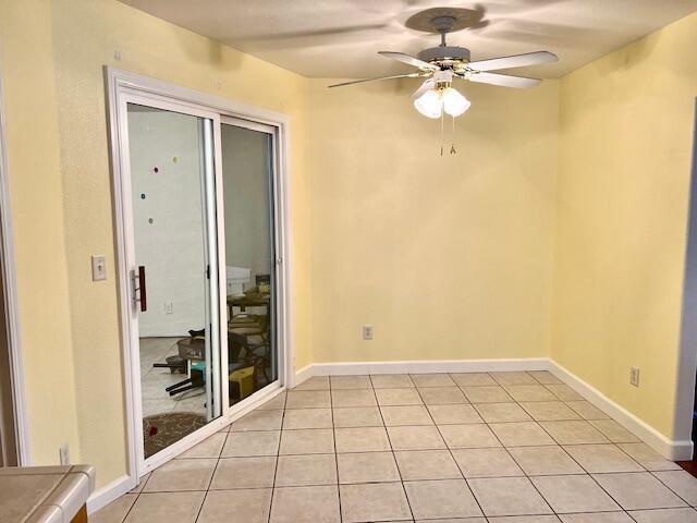 empty room featuring light tile patterned floors, ceiling fan, and baseboards