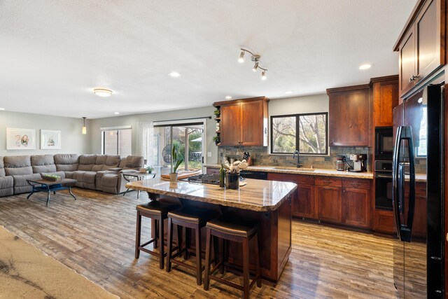 3300 Forest Hills Dr, Redding, CA 96002 - kitchen with black appliances, a sink, light wood-style flooring, and a kitchen breakfast bar