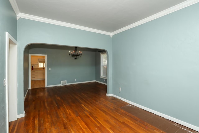 spare room featuring arched walkways, crown molding, visible vents, wood finished floors, and baseboards